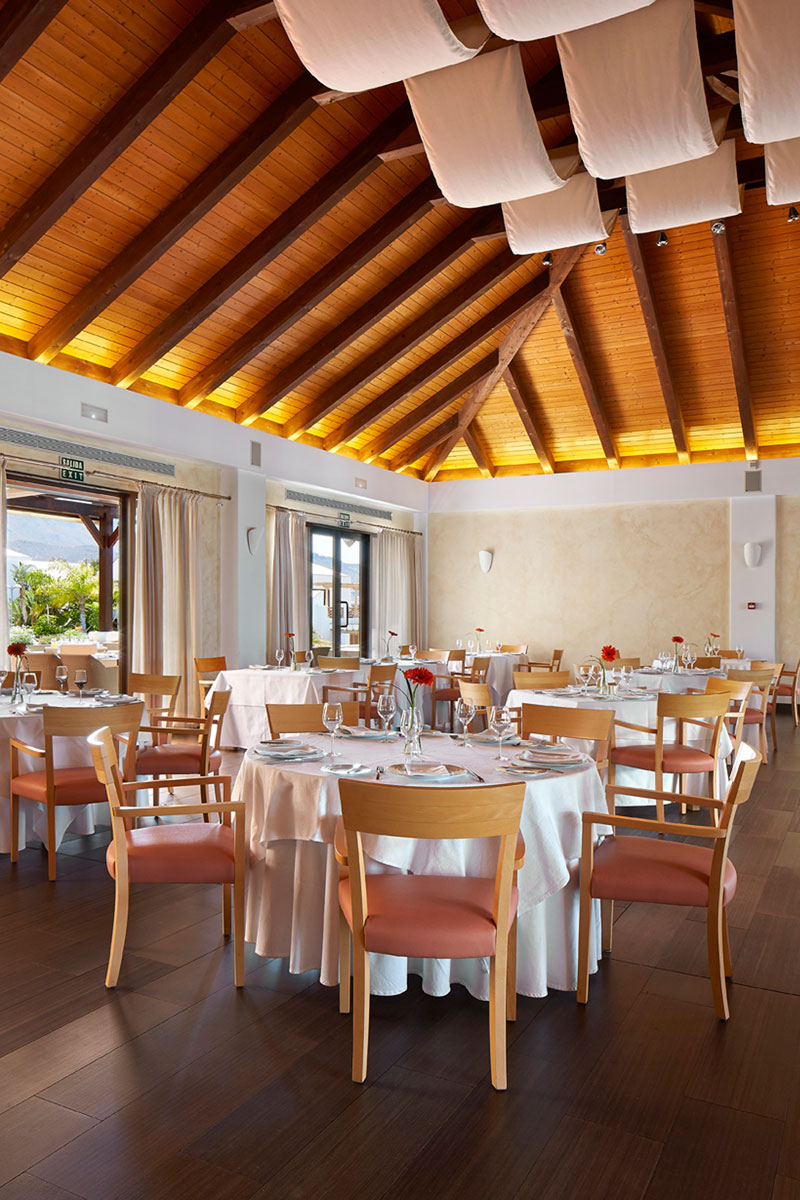 Restaurant met houten dak en tafels in Tenerife, zichtbare nooduitgang.