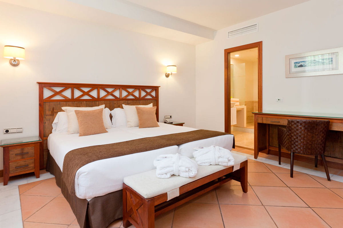 Hotelkamer met tweepersoonsbed, kaptafel en toegang tot de badkamer op Tenerife.