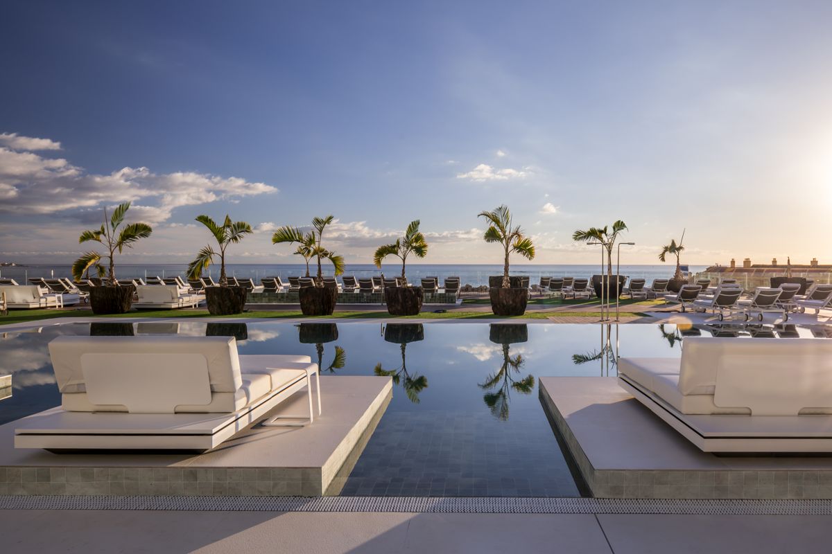 Infinity zwembad met ligstoelen en palmbomen met uitzicht op zee op Tenerife.