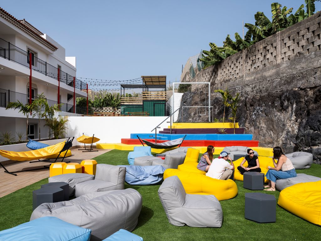 Mensen praten in de buitenruimte met hangmatten en kleurrijke zitzakken op Tenerife.