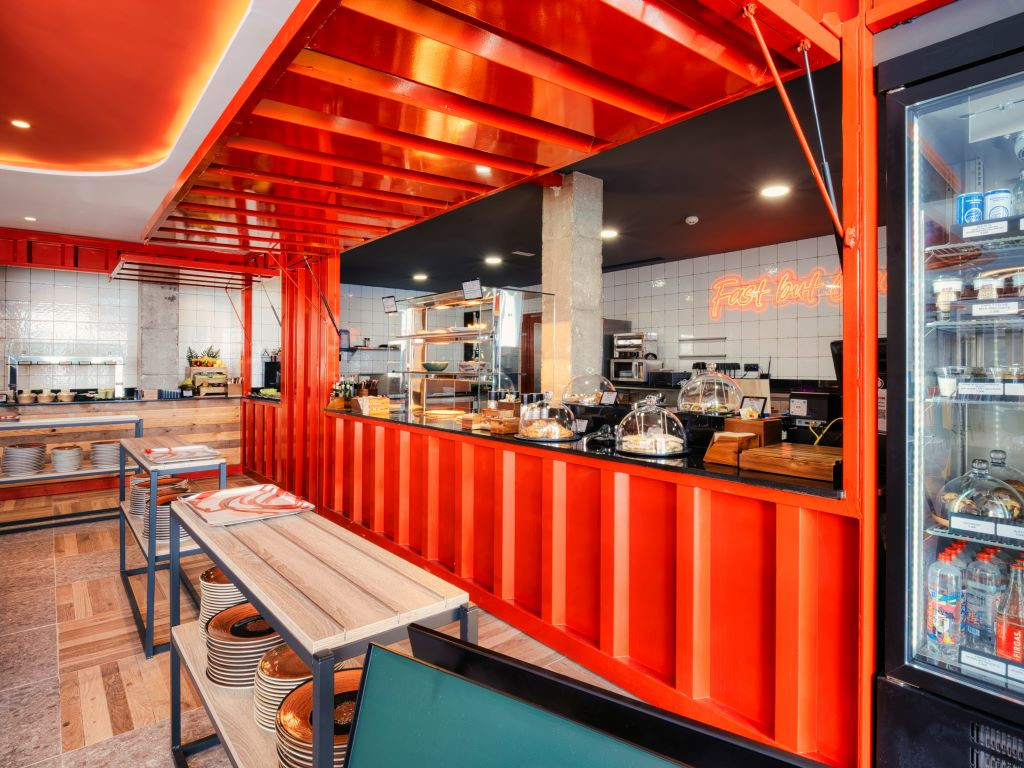 Interieur van een restaurant op Tenerife met houten tafels en een rode toonbank.