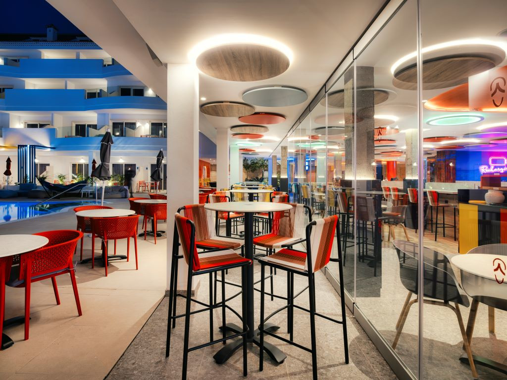 Terras van een restaurant met rode tafels en stoelen in een hotel op Tenerife 's nachts.
