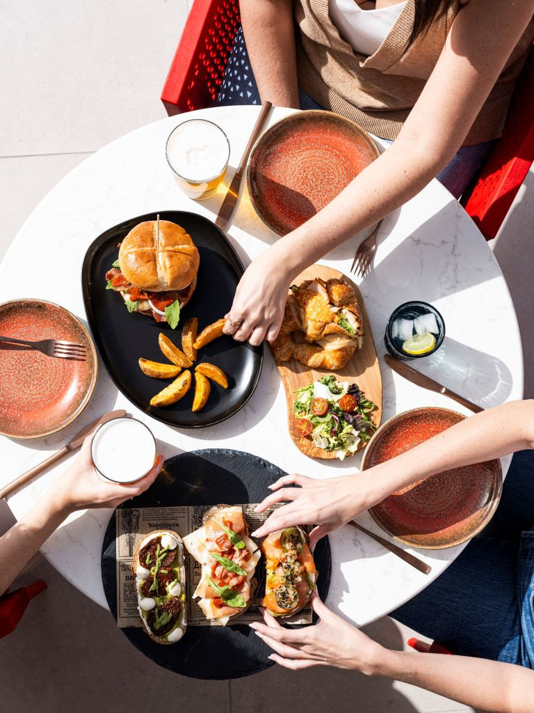 Tafel met hamburger, frietjes, salade en drankjes in een restaurant op Tenerife.