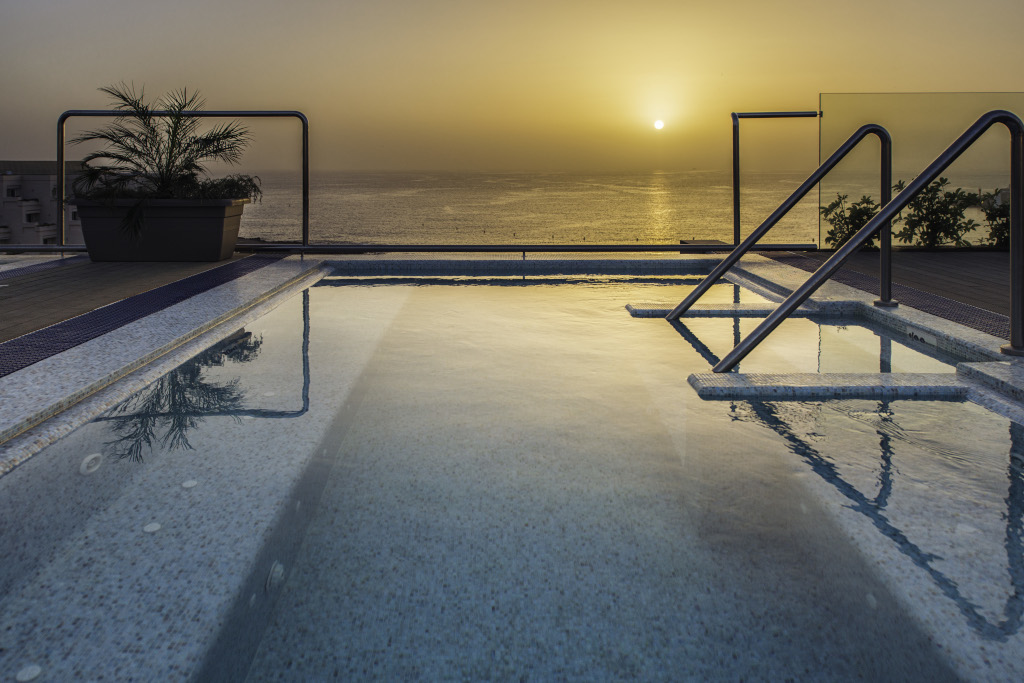Dakzwembad bij zonsondergang met zeezicht op Tenerife.