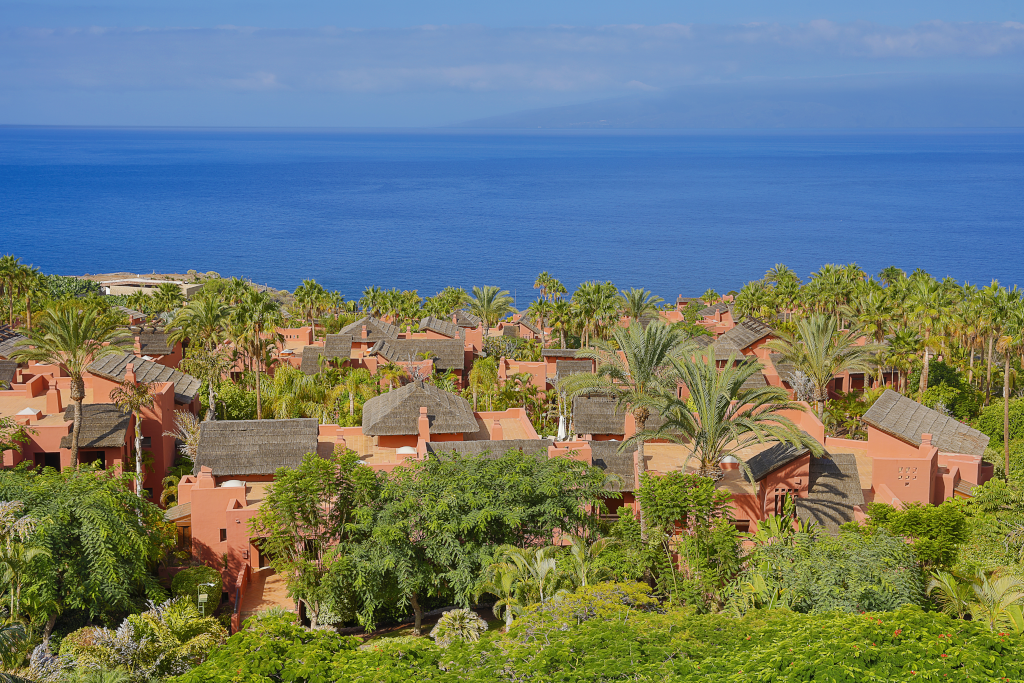Complex van huizen met rieten daken en groen met uitzicht op zee op Tenerife.