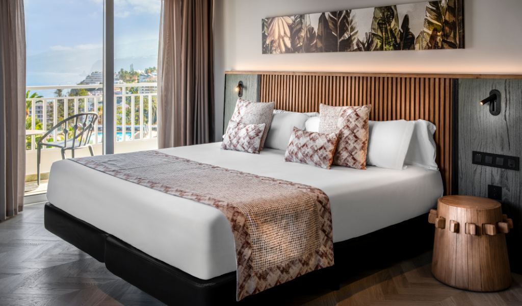 Kamer met tweepersoonsbed, zeezicht en plantendecoratie op Tenerife.