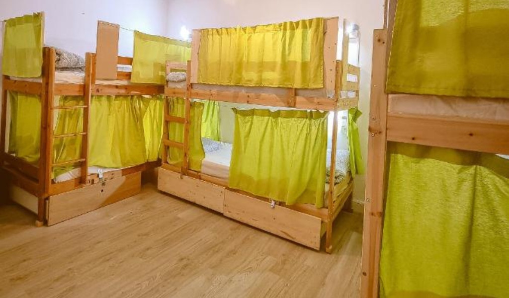 Houten stapelbedden met groene gordijnen in een gedeeld slaapvertrek op Tenerife.