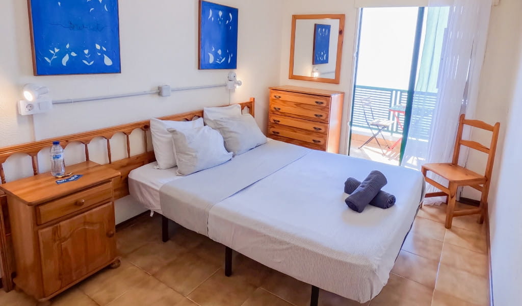 Slaapkamer op Tenerife met bed, nachtkastje, ladekast en balkon.