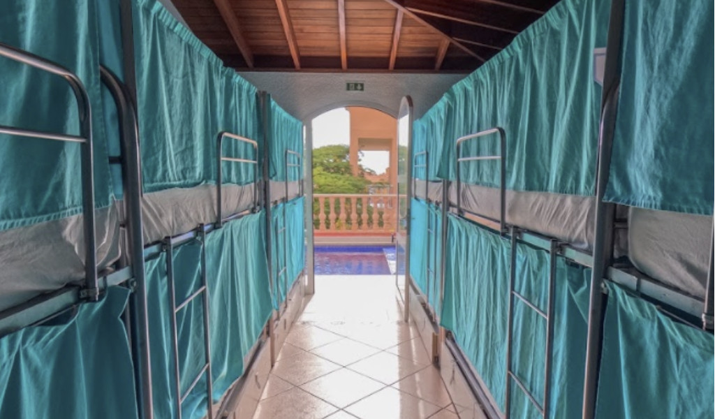 Stapelbedden in een gang met groene gordijnen in een hostel op Tenerife.