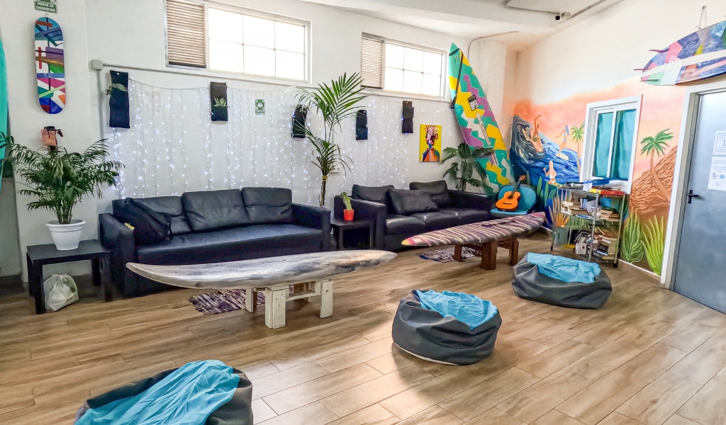 Woonkamer met banken, surfplanken en kleurrijke muurschilderingen in een hostel op Tenerife.
