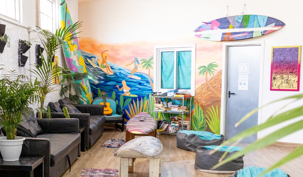 Woonkamer versierd met kleurrijke muurschilderingen en planten in een surfhuis op Tenerife.