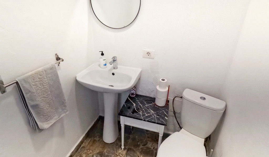 Kleine badkamer met wastafel, ronde spiegel en een toilet op Tenerife.
