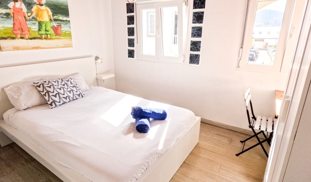 Kamer met tweepersoonsbed, raam, stoel en schilderij aan de muur in Santa Cruz de Tenerife.