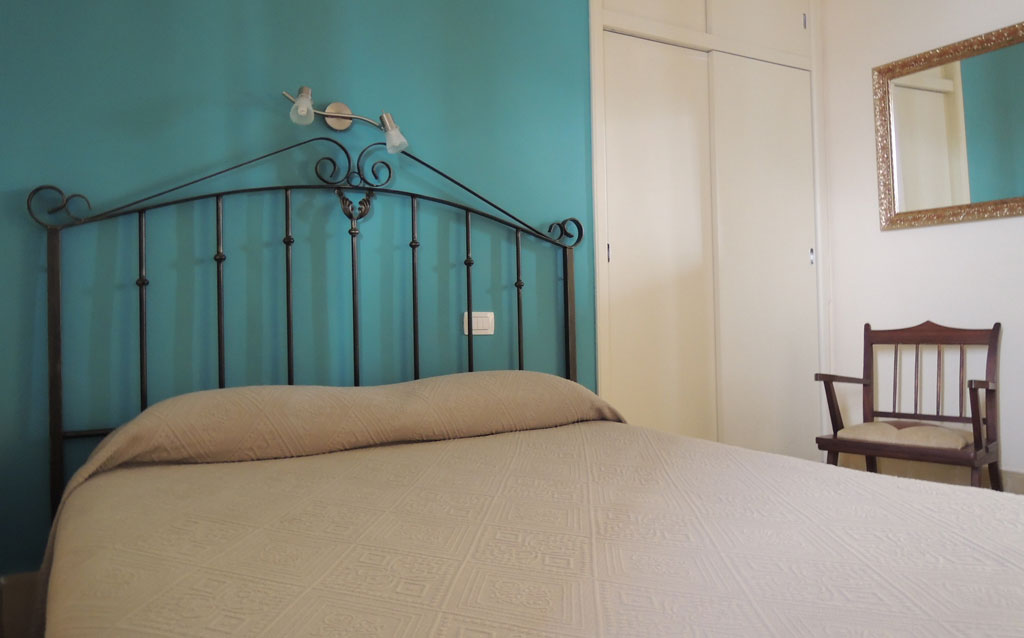 Bed in kamer met metalen hoofdeinde en blauwe muur op Tenerife.