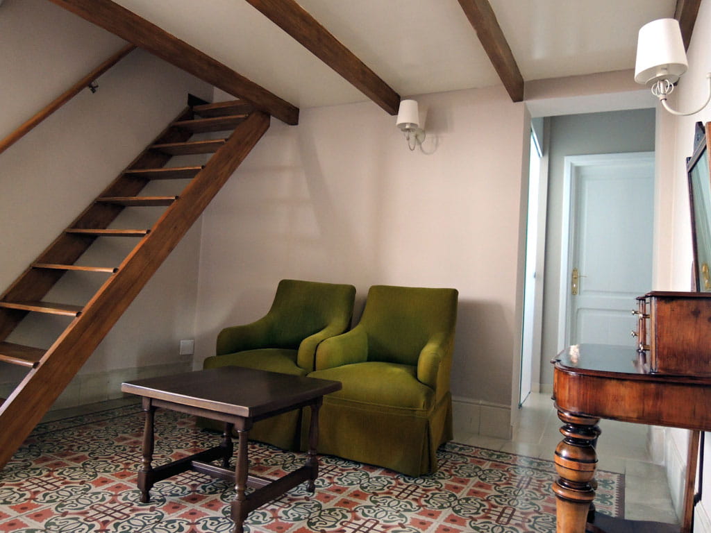 Woonkamer met groene stoelen, houten tafel en trap op Tenerife.