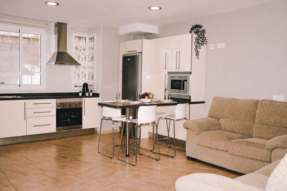 Moderne keuken met woonkamer, tafel en bank in een appartement op Tenerife.
