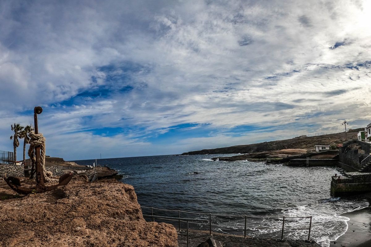 Rotsachtige kust met anker en zee in Tajao, Tenerife, onder een bewolkte lucht.