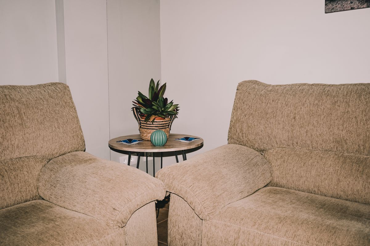 Beige banken in de woonkamer met centrale tafel en plant op Tenerife.