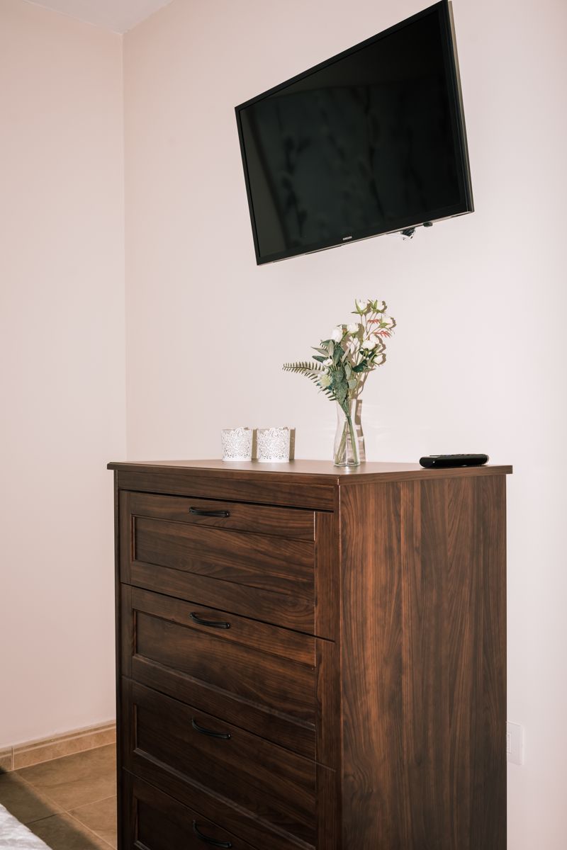 Muur-tv op de ladekast met bloemenvaas in een kamer op Tenerife.