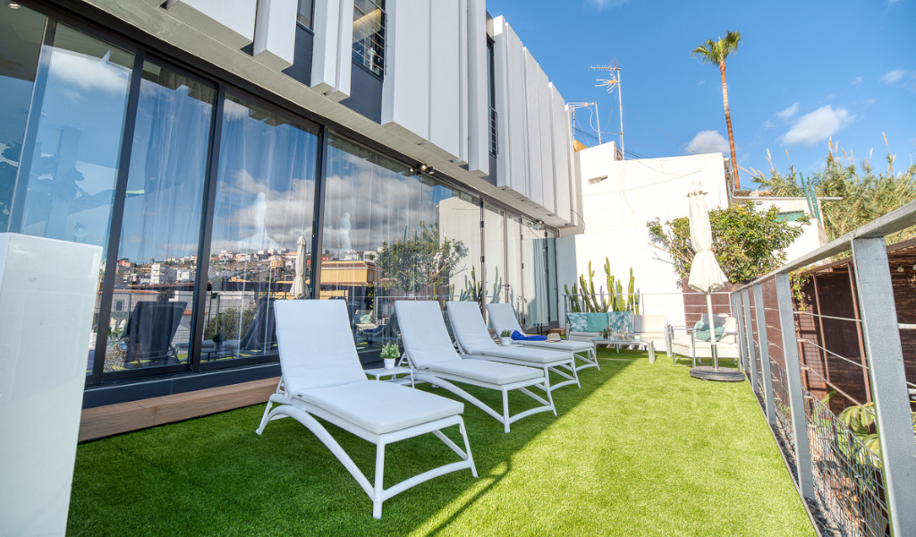 Witte ligstoelen op het terras van Tenerife met stedelijk landschap op de achtergrond.