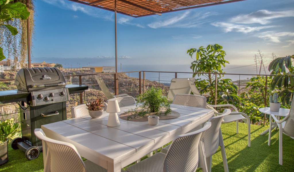 Terras met witte tafel en stoelen, zeezicht en barbecue op Tenerife.