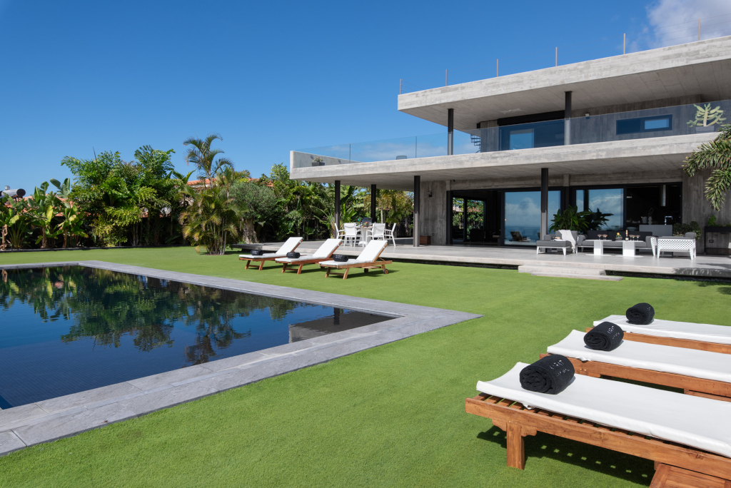 Zwembad en ligstoelen in de tuin van een modern huis op Tenerife.