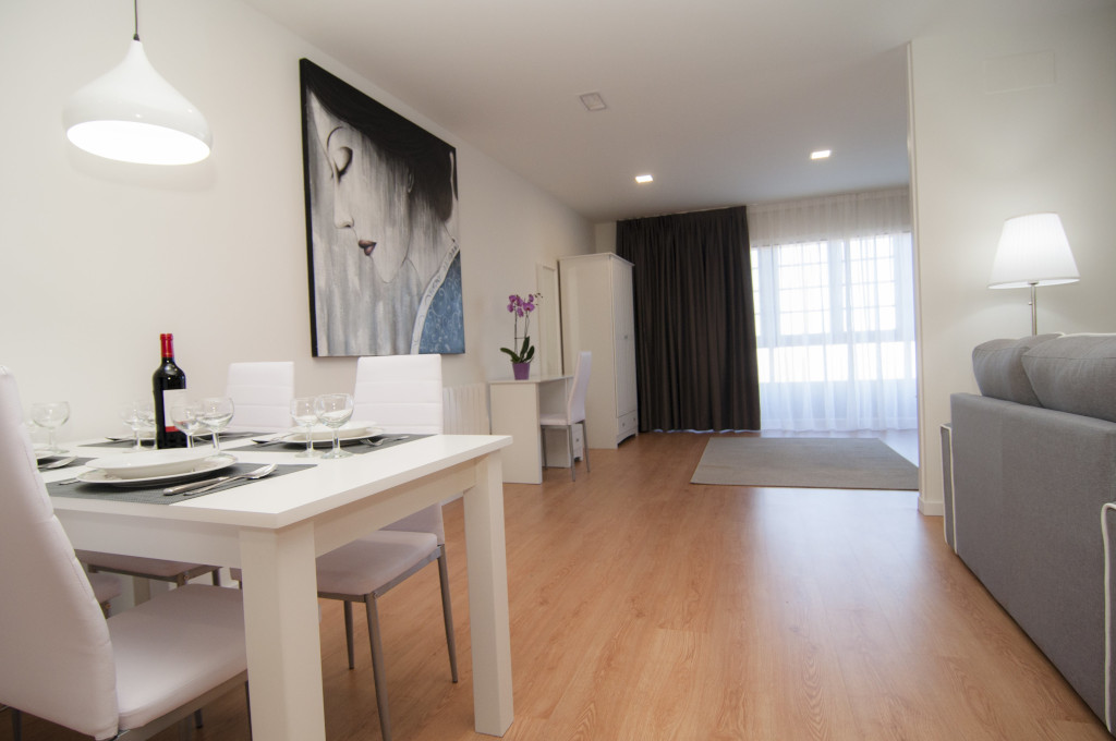Eetkamer met witte tafel, stoelen, een fles wijn en een schilderij in een appartement op Tenerife.