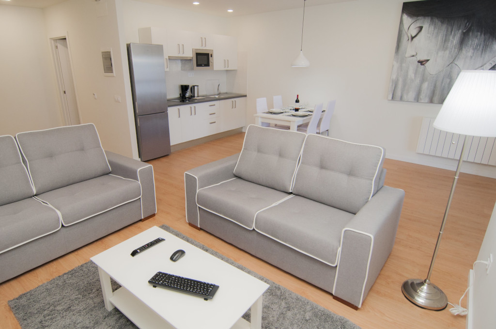 Woonkamer met grijze fauteuils, eettafel en keuken in een appartement op Tenerife.