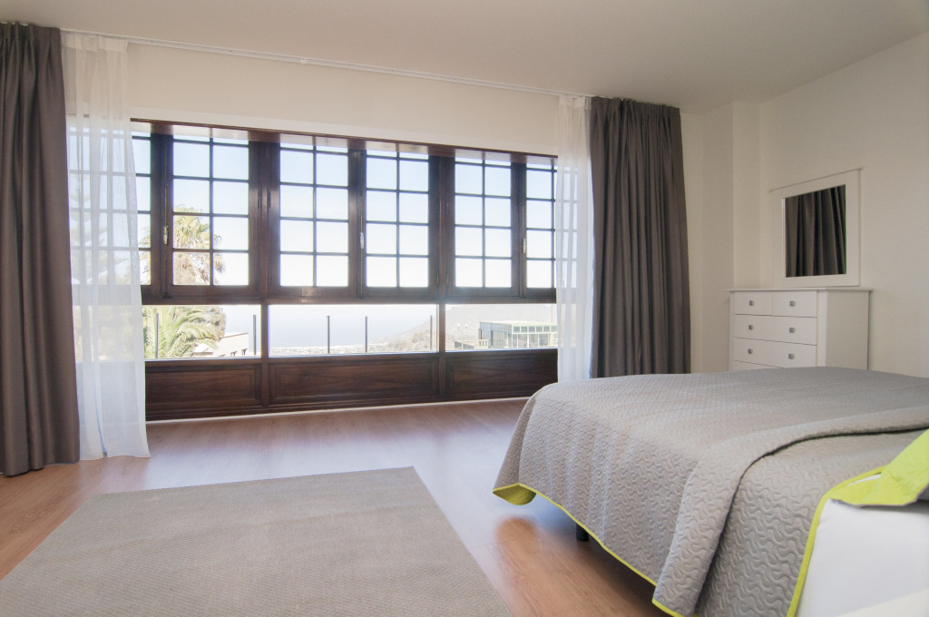 Kamer met bed, grote ramen en zeezicht op Tenerife.