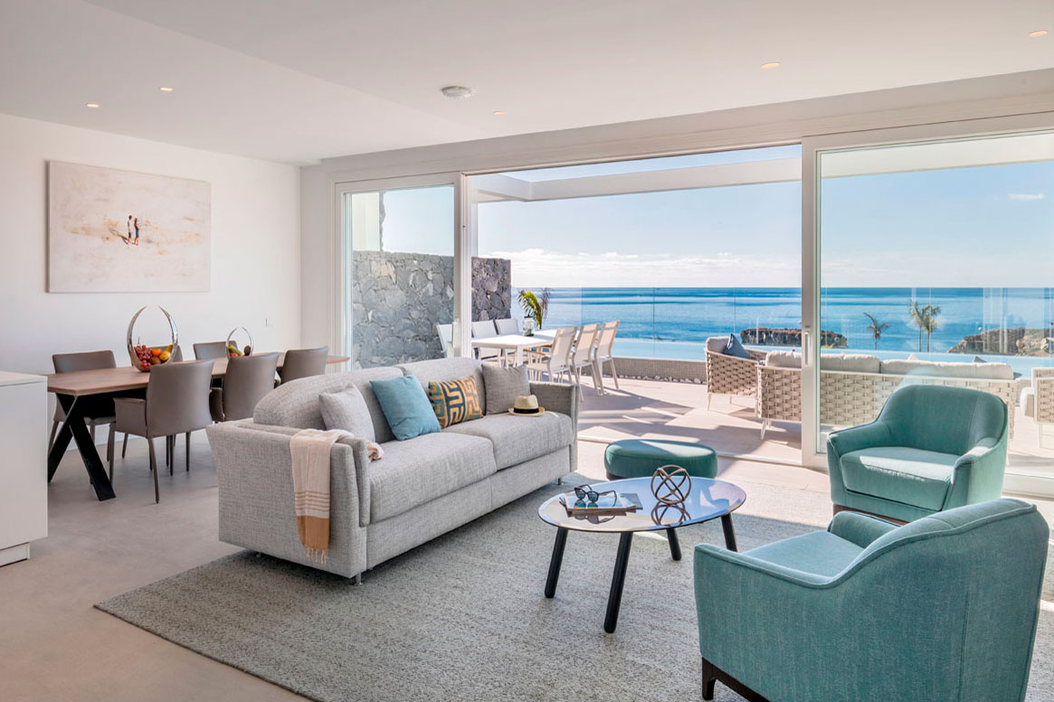 Moderne woonkamer met zeezicht op Tenerife. Grijze bank, blauwe stoelen en tafel.