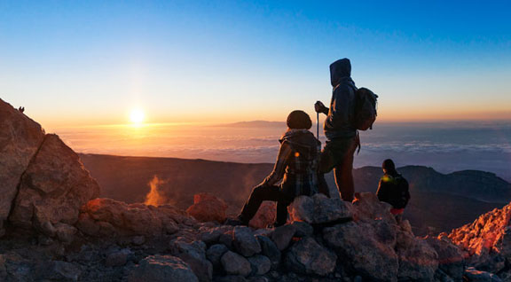 Mensen kijken naar een zonsopgang op de berg Teide, Tenerife, vanaf een rotsachtige top.
