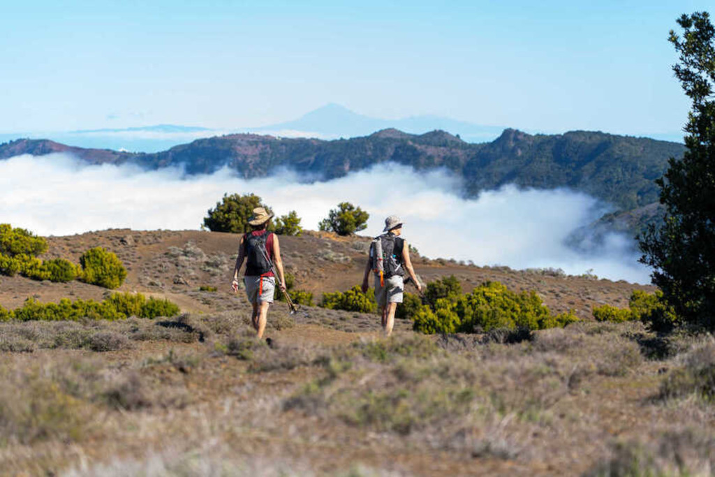 Twee mensen die tussen bergen en wolken lopen op Tenerife.