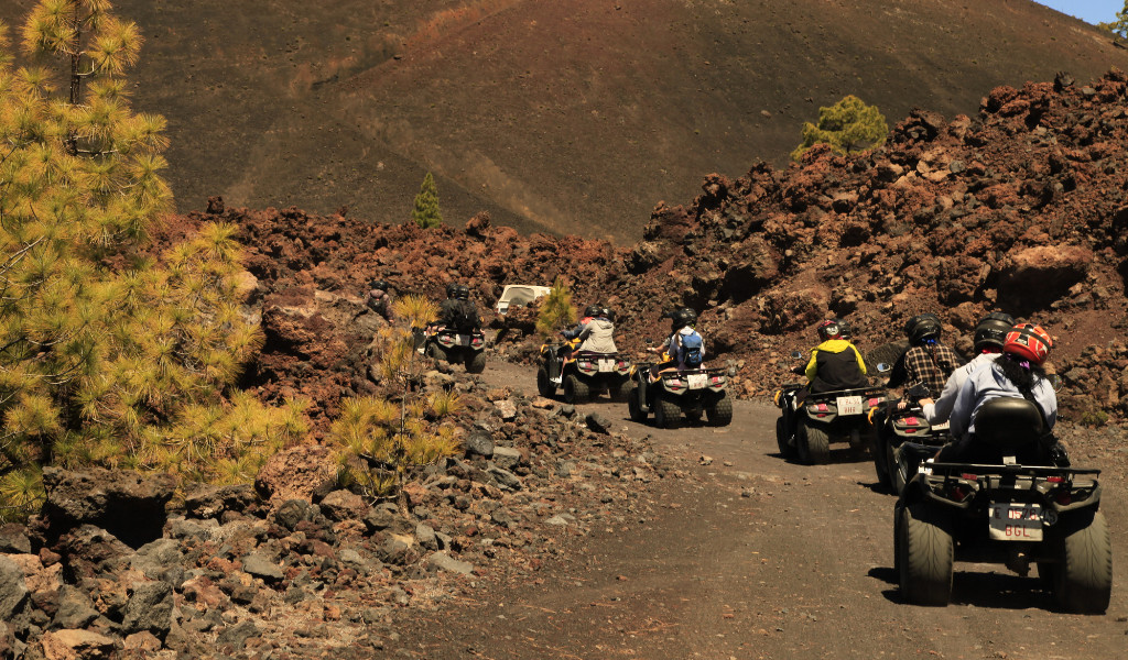 Groep op quads die een vulkanisch pad op Tenerife afleggen.
