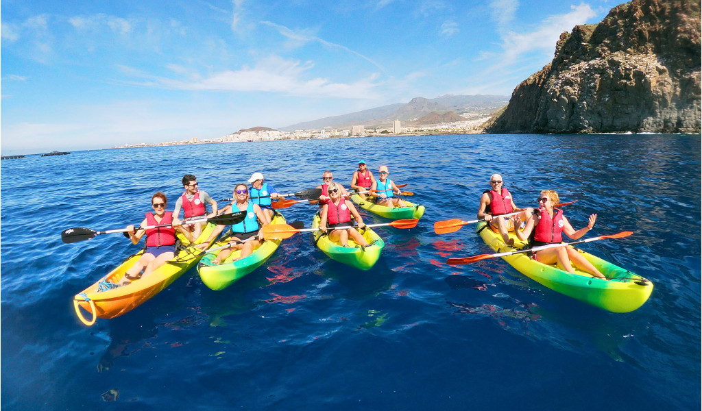 Groepskajakken in het water van Tenerife met bergen op de achtergrond.