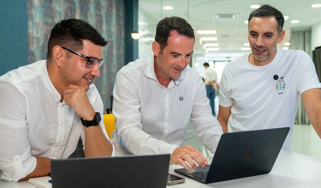 Drie mannen werken samen voor een computer in een kantoor op Tenerife.