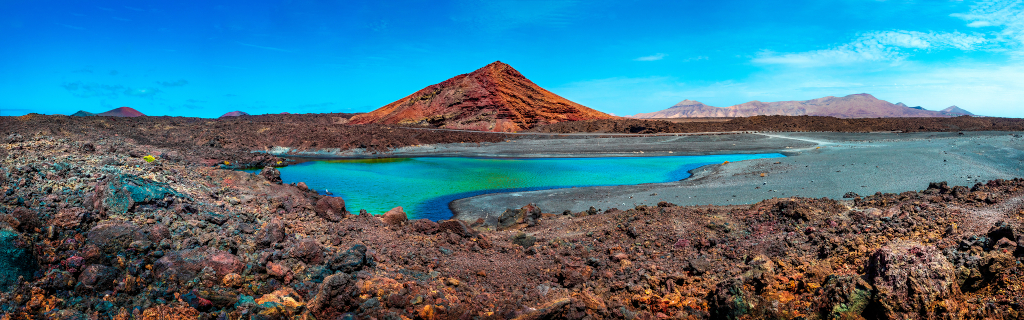 Groenachtig meer omgeven door vulkanische grond met bergen op de achtergrond op Tenerife.
