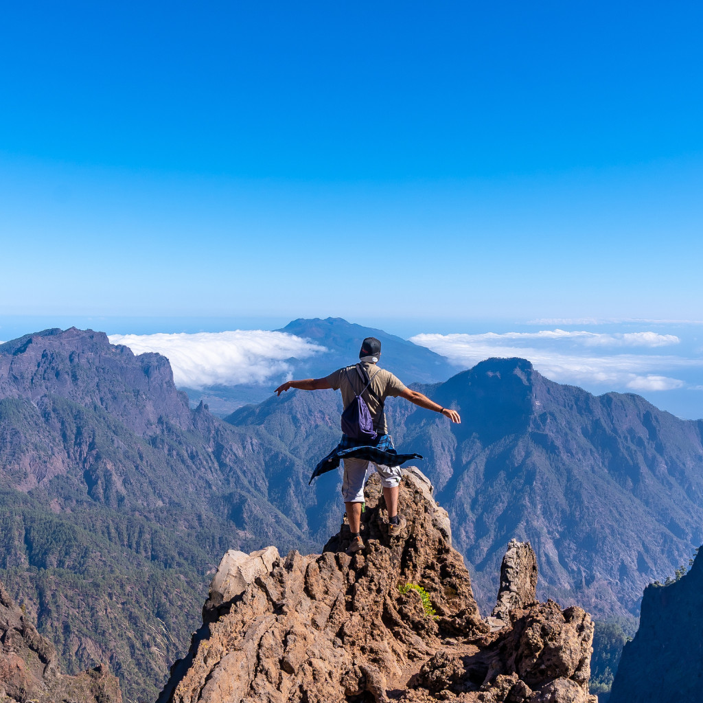 Persoon met rugzak bovenop de berg met uitzicht op de landschappen van Tenerife.
