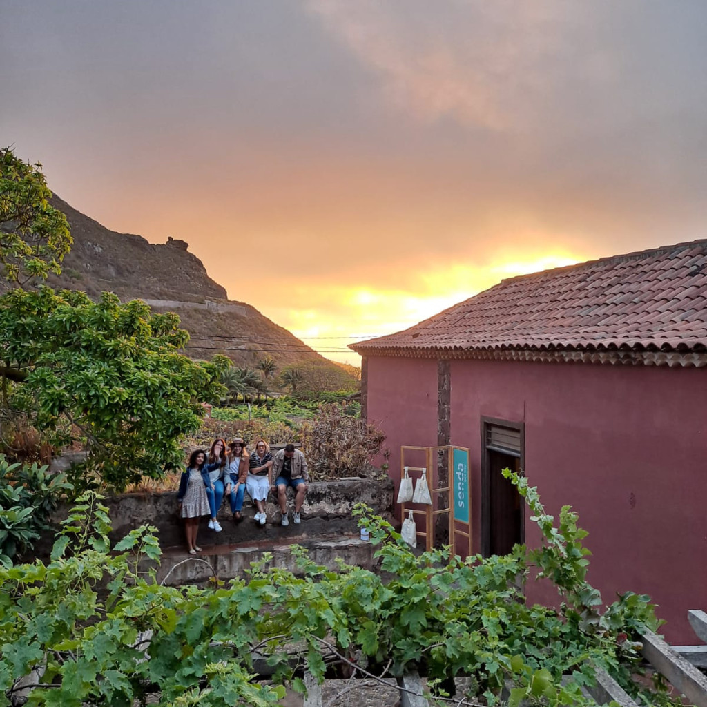 Groep mensen die bij zonsondergang in een tuin op Tenerife zit, met een bordpad.