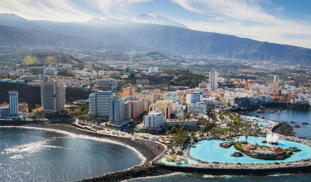Luchtfoto van Puerto de la Cruz, Tenerife, met kustlijn en hoge gebouwen.