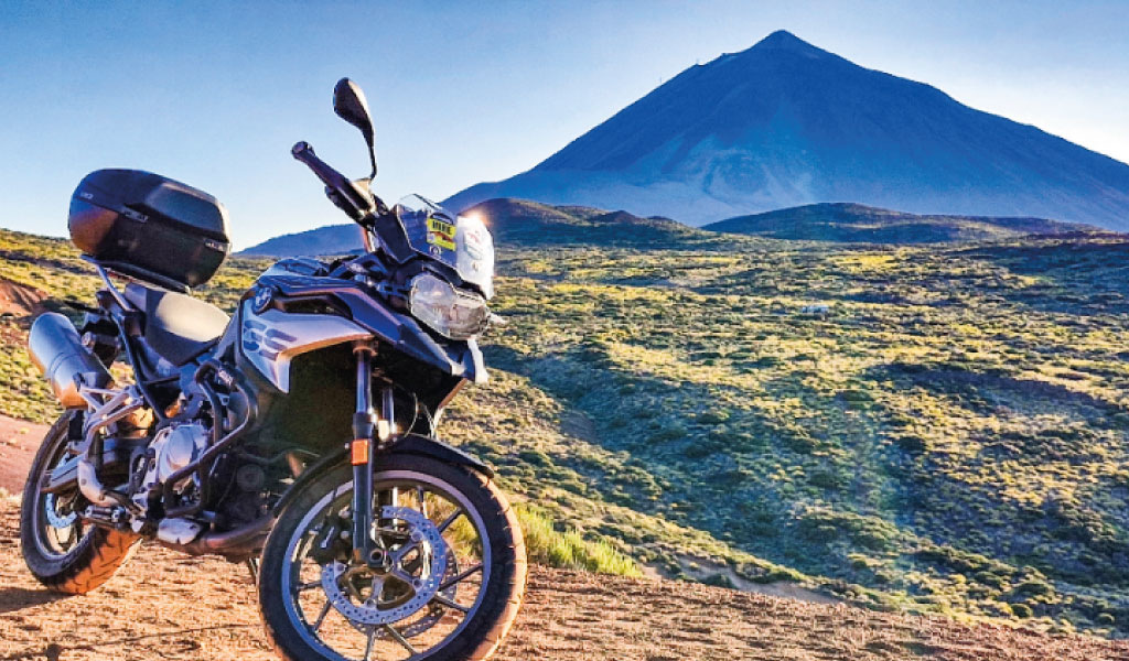 Motorfiets geparkeerd voor de berg Teide op Tenerife onder een blauwe lucht.