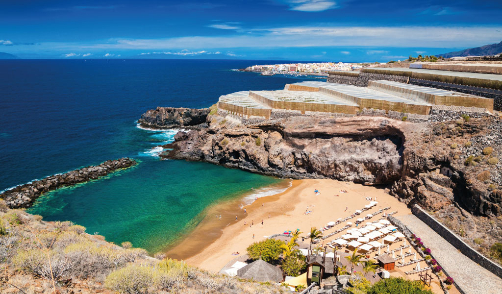 Strand met parasols en blauwe zee in Puerto de Santiago, Tenerife.