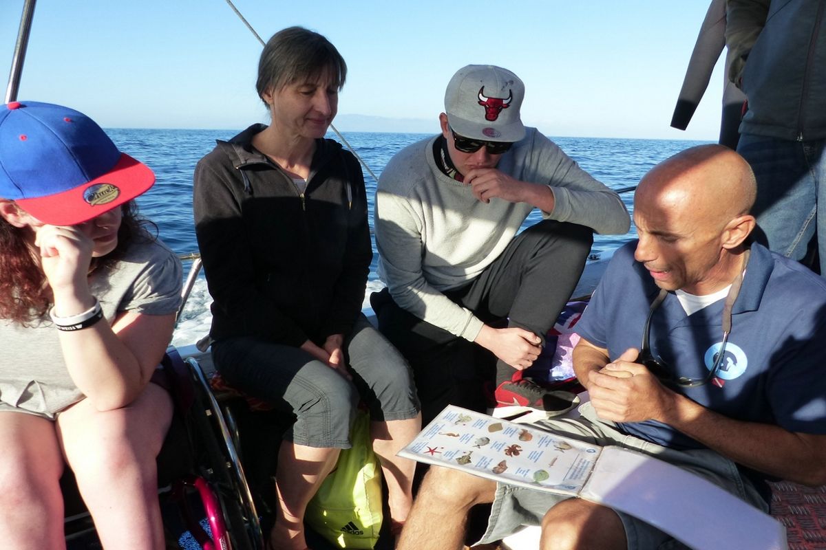 Mensen op een boot op Tenerife bekijken een lijst met afbeeldingen en tekst terwijl ze varen.