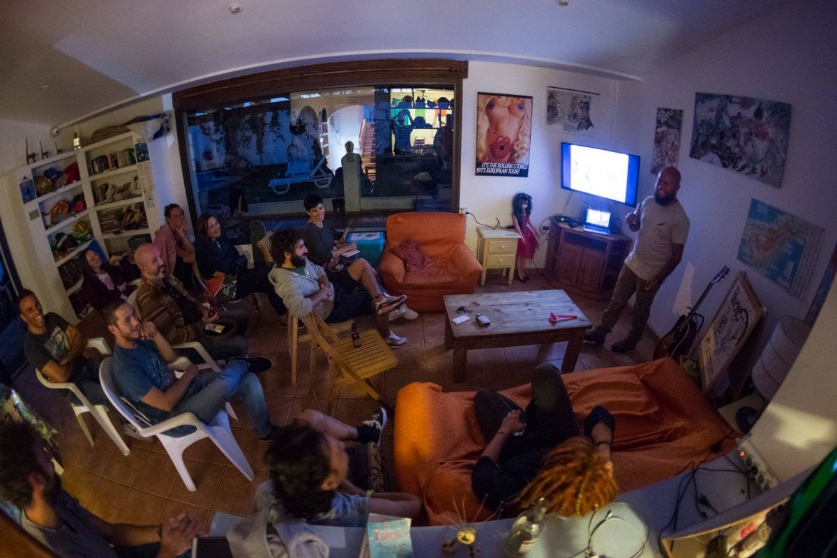 Groep mensen die een presentatie bijwoont in een woonkamer op Tenerife.