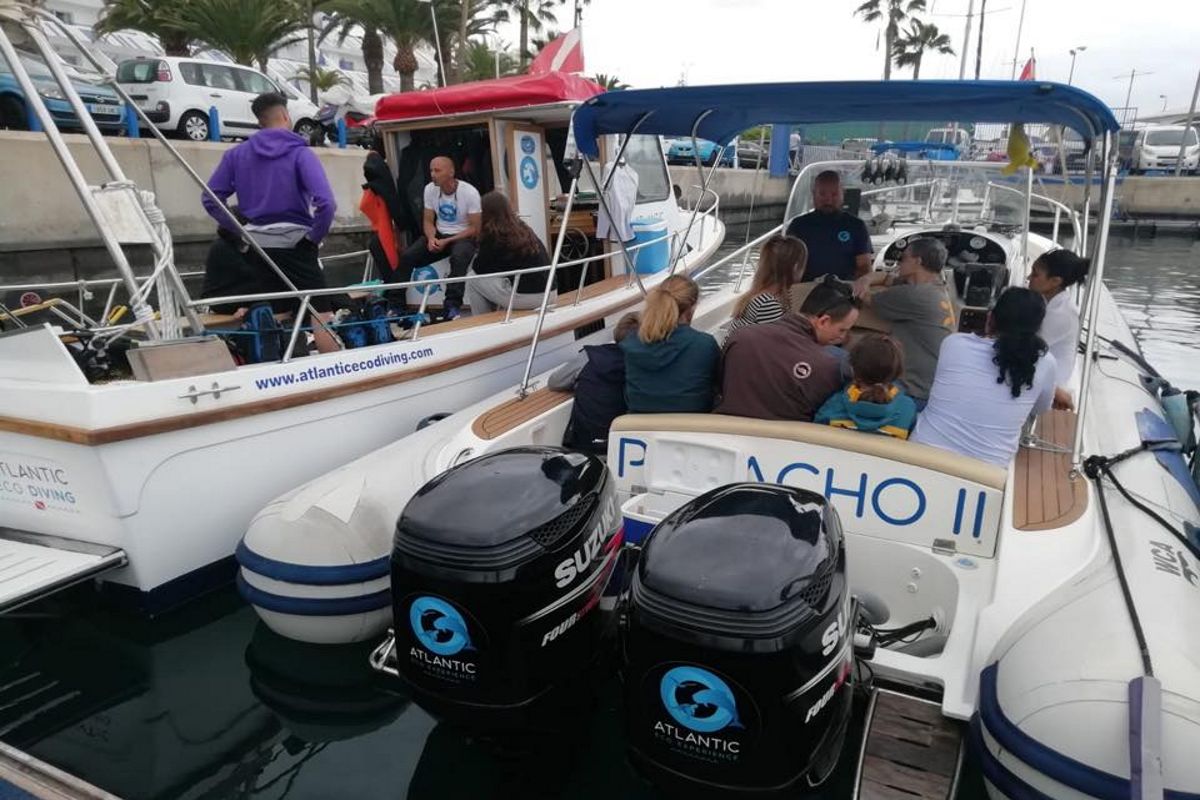 Groep mensen op een toeristenboot op Tenerife, met Suzuki-motoren en het Atlantic Eco Diving-logo.