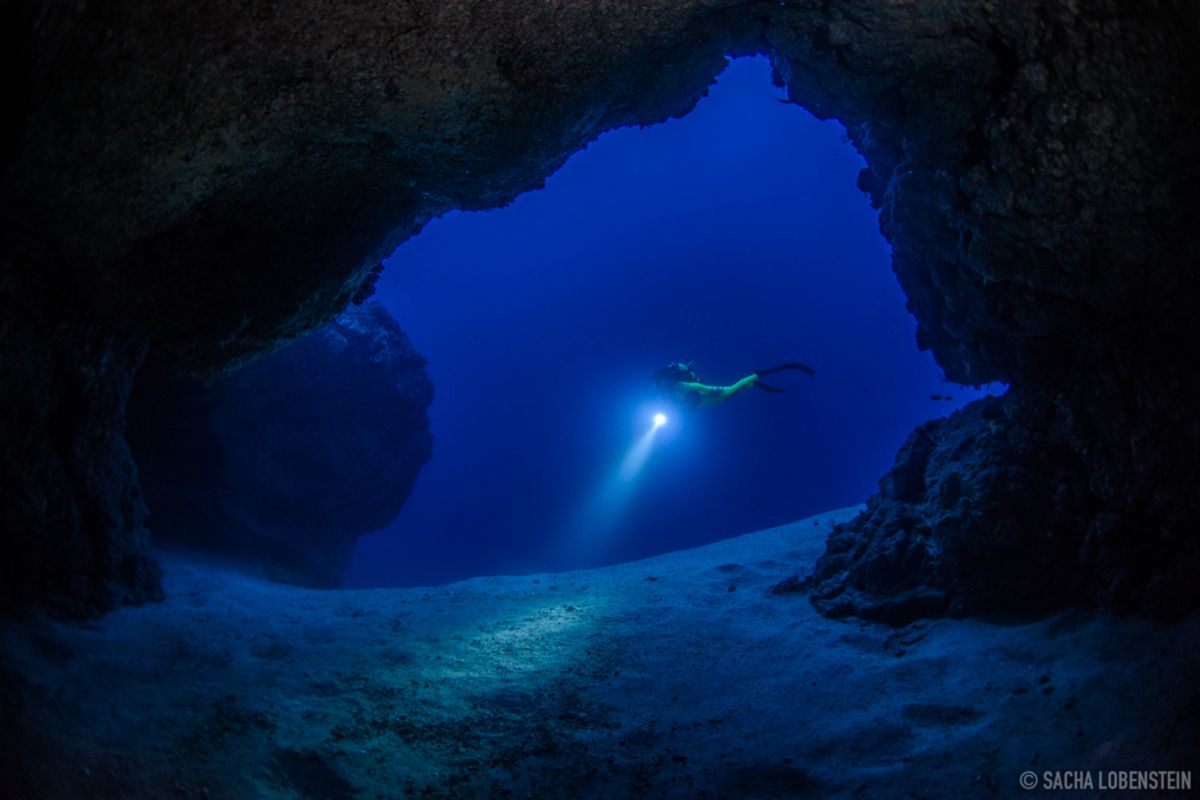 Onderwatergrottenduiker die de zeebodem op Tenerife verlicht.