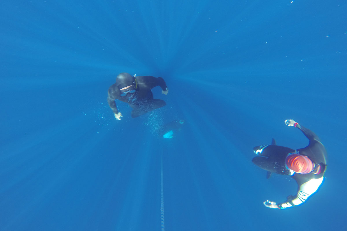 Duikers in het water van Tenerife, één met een rood wetsuit.