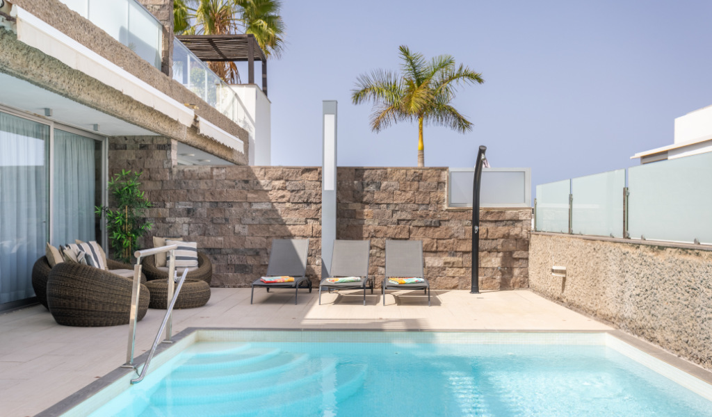 Buitenzwembad met stoelen en palmboom in een hotel op Tenerife.