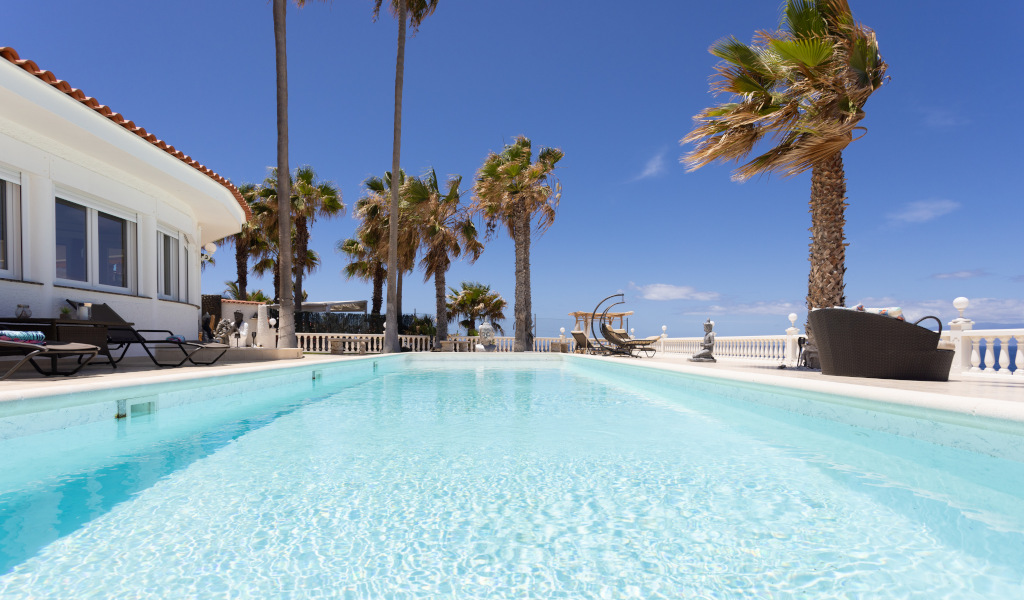 Buitenzwembad met palmbomen op Tenerife onder een heldere lucht.