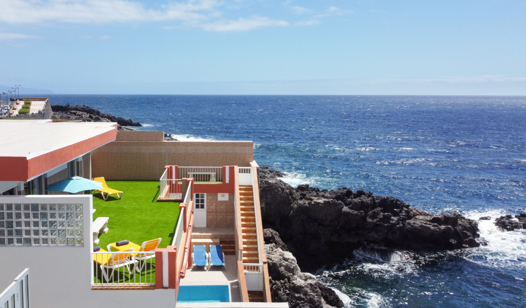 Terras met gazon en ligstoelen aan zee op een klif op Tenerife.