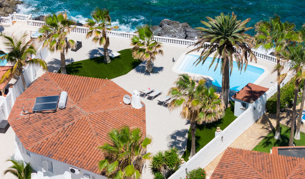 Luchtfoto van terras met zwembad, palmbomen en zee op Tenerife.